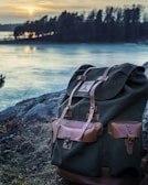A backpack resting on a rocky surface with a beautiful sunset in the background.