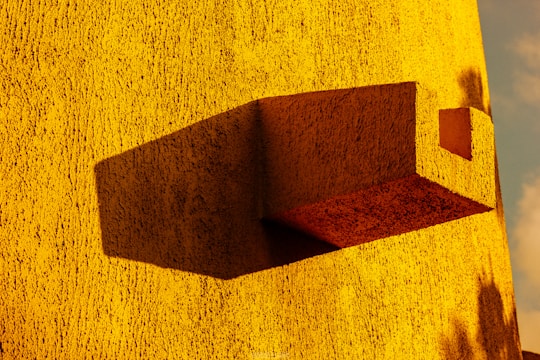 Abstract architectural sculpture with layered shadows and warm yellow accents on a dark background.