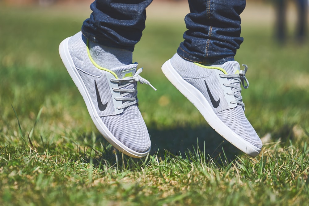 pair of gray Nike low-top sneakers hanging on green grass