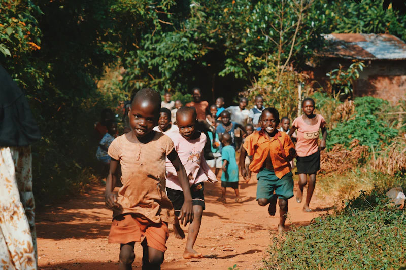 Children running along a sandy path between trees