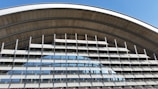 An architectural structure featuring a series of horizontal louvered panels arranged in an arc. The design allows for both functionality and aesthetics, with metallic elements and large glass windows reflecting the sky. The structure appears modern and utilitarian.