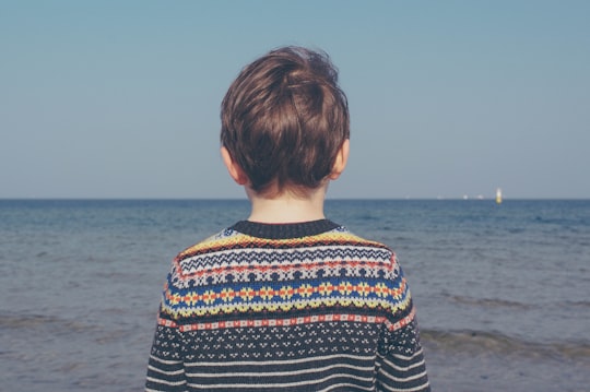 person wearing multicolored striped floral sweater facing the sea in Sopot Poland