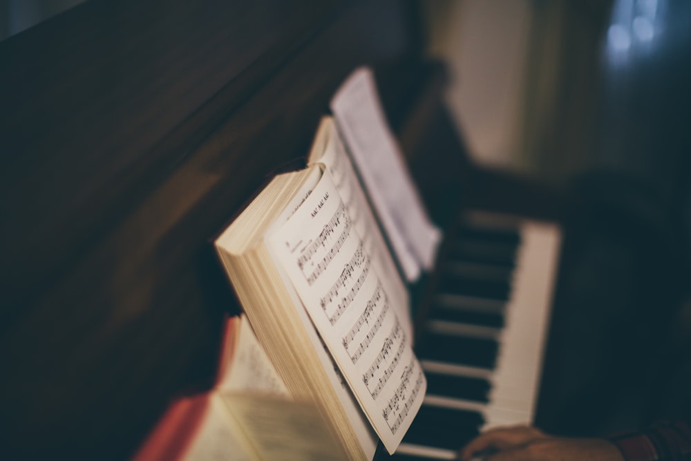 opened music sheet book on top of upright piano