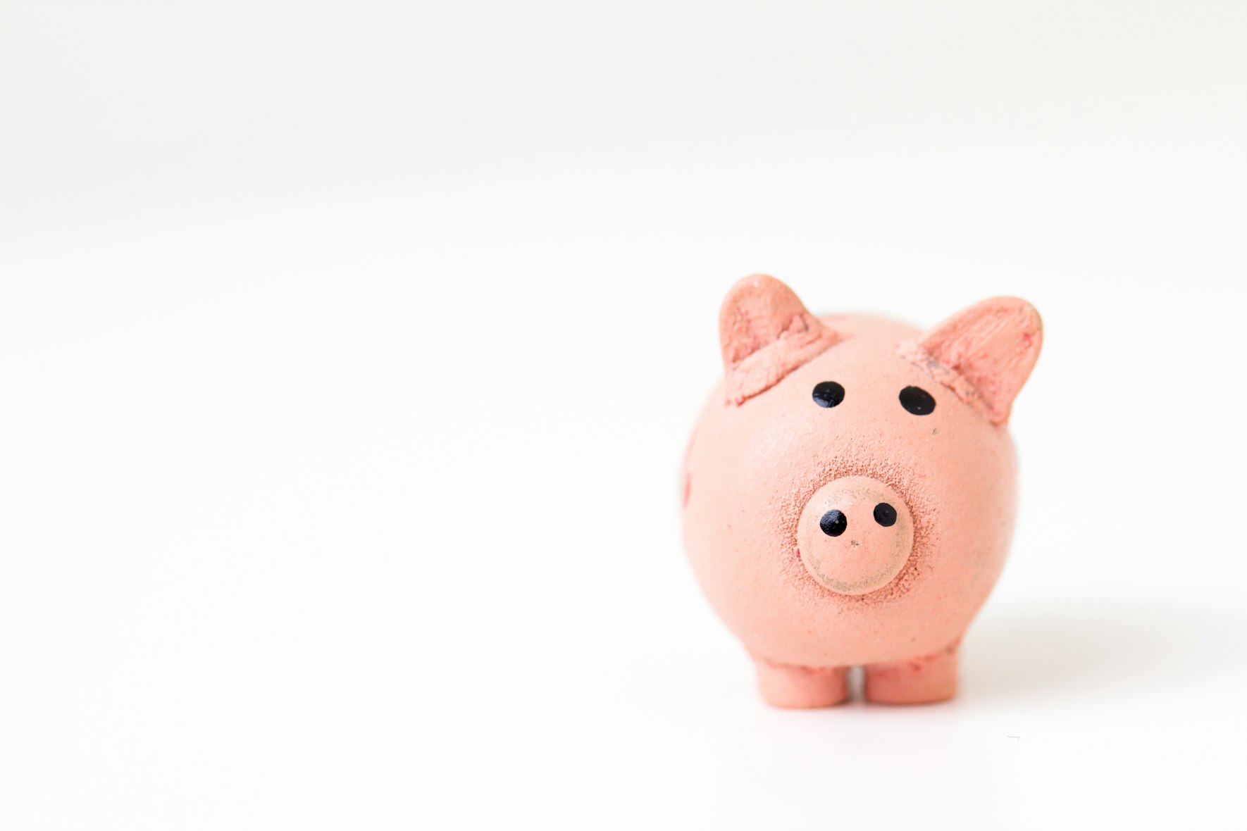Image is of a pink piggy bank off to the side on a white background