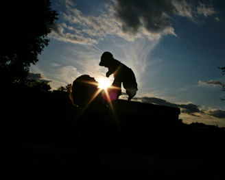 Silhouette of a father lifting his daughter high against a warm, glowing sunset.