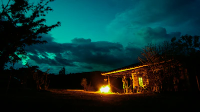 Evening glow casting soft light on cozy cabin with smoke from chimney.
