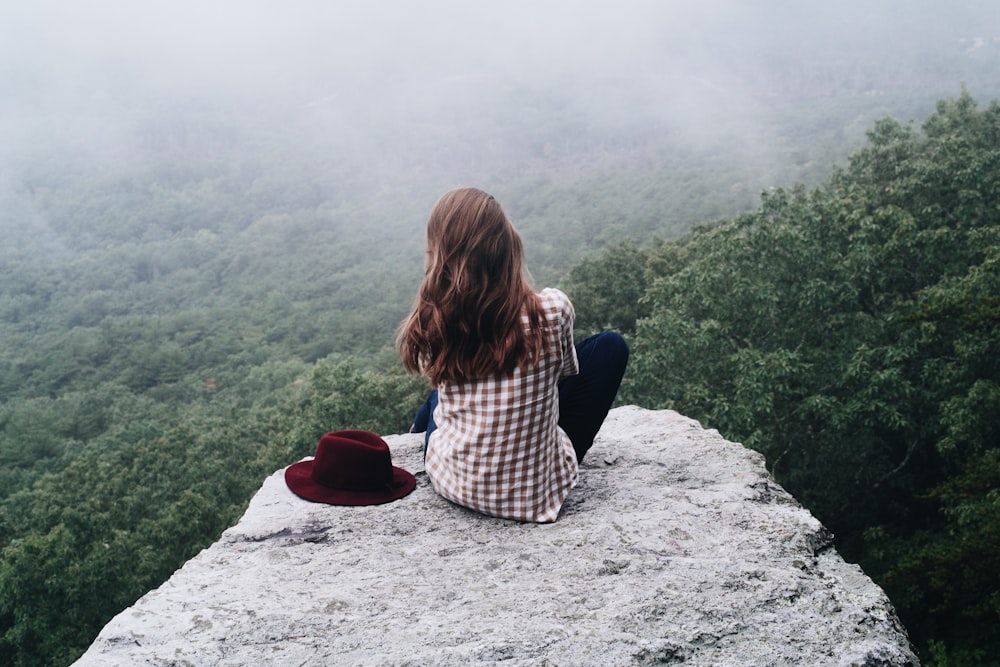 Frau sitzt auf grauem Felsen