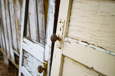 A row of finished wooden doors leaning against a rustic wall.