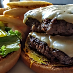 A close-up of a juicy cheeseburger with melted cheese, fresh lettuce, and crispy fries on the side.