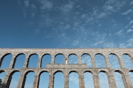 A beautifully preserved Roman aqueduct against a blue sky.