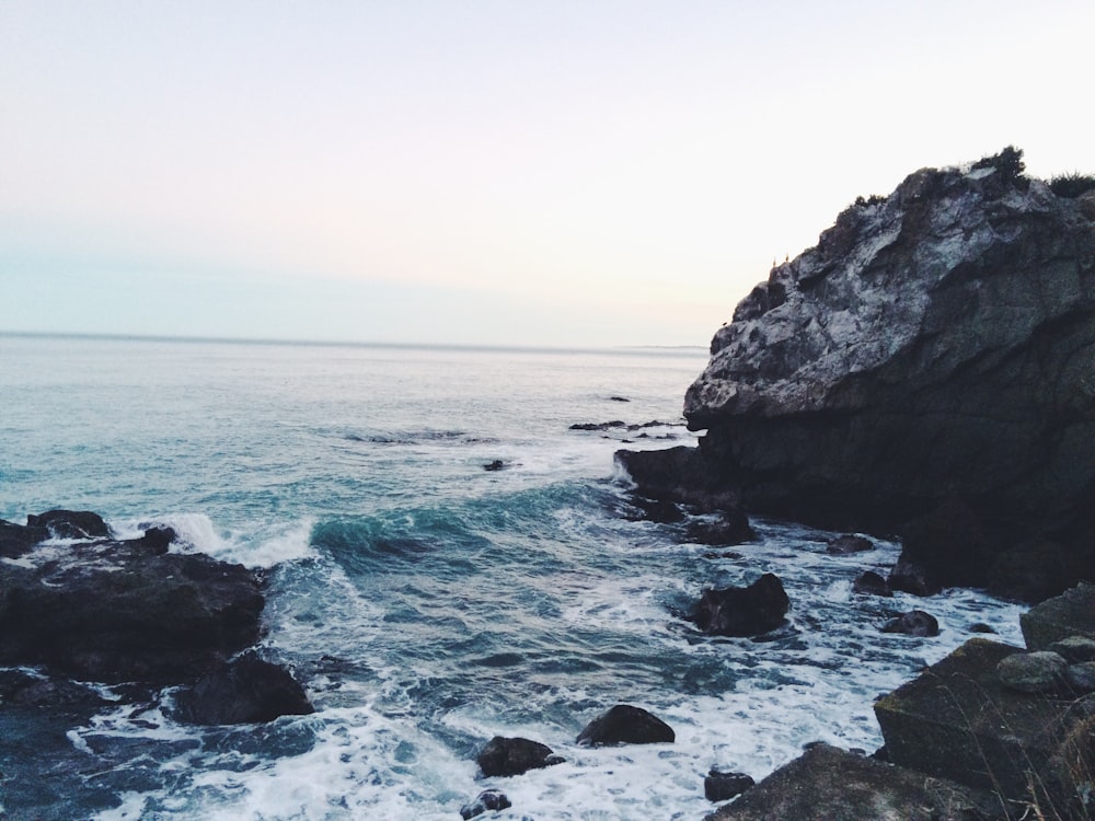 ocean waves near rocks during daytime