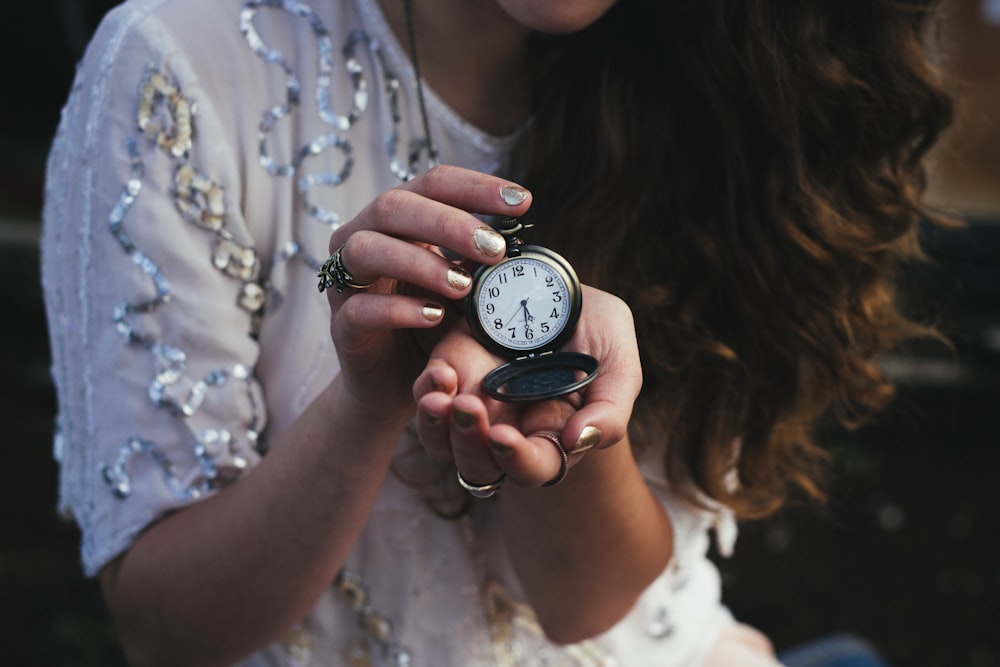 Mujer sosteniendo reloj de bolsillo negro a las 5:30
