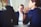 Three people are sitting at a table, engaged in a discussion. Two individuals are facing away from the camera, while one person is facing the camera attentively, appearing to listen intently. The setting appears professional, likely a meeting or interview.