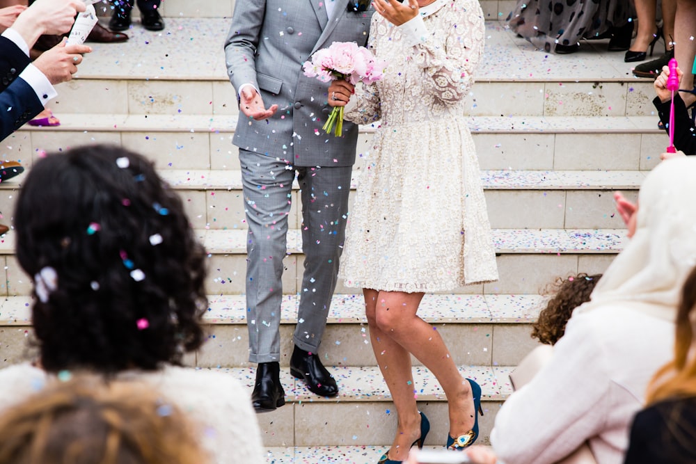 Crowd of well-wishers throws glitter onto newlyweds descending a staircase