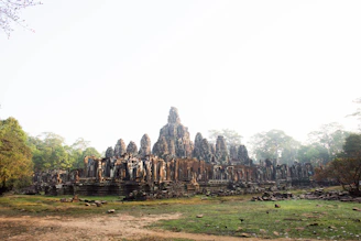 Ancient temple ruins framed by lush greenery and soft morning mist