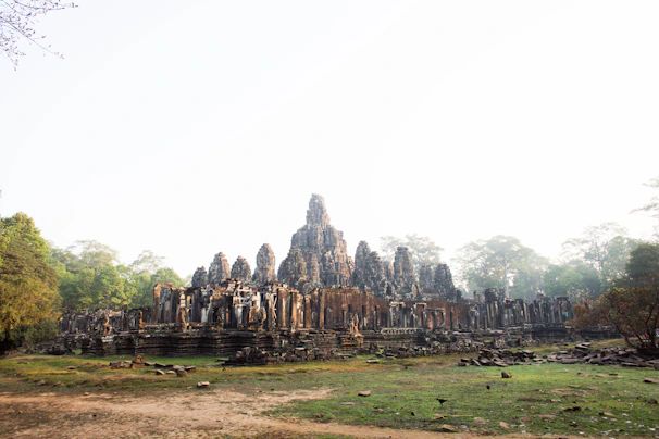 An ancient temple carved into a mountainside, surrounded by lush greenery and mist