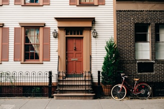 red bicycle parked beside black metal gate in front house