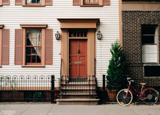 red bicycle parked beside black metal gate in front house