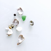 Close-up of a handmade artwork featuring small stones, shells, and feathers arranged harmoniously on a natural background.