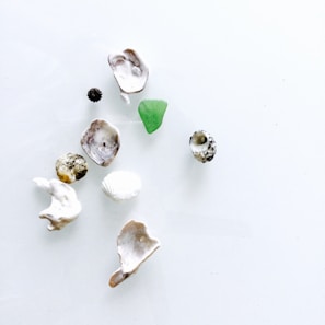 Close-up of a handmade artwork featuring small stones, shells, and feathers arranged harmoniously on a natural background.