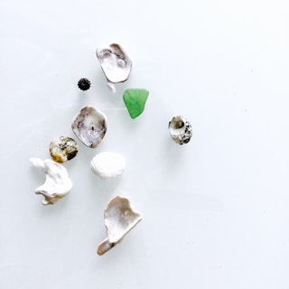 Close-up of a handmade artwork featuring small stones, shells, and feathers arranged harmoniously on a natural background.