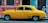 yellow sedan parked near red concrete building