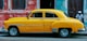 yellow sedan parked near red concrete building
