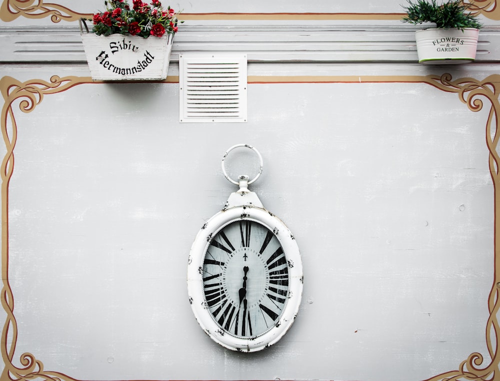 oval white analog clock display at 6 o'clock