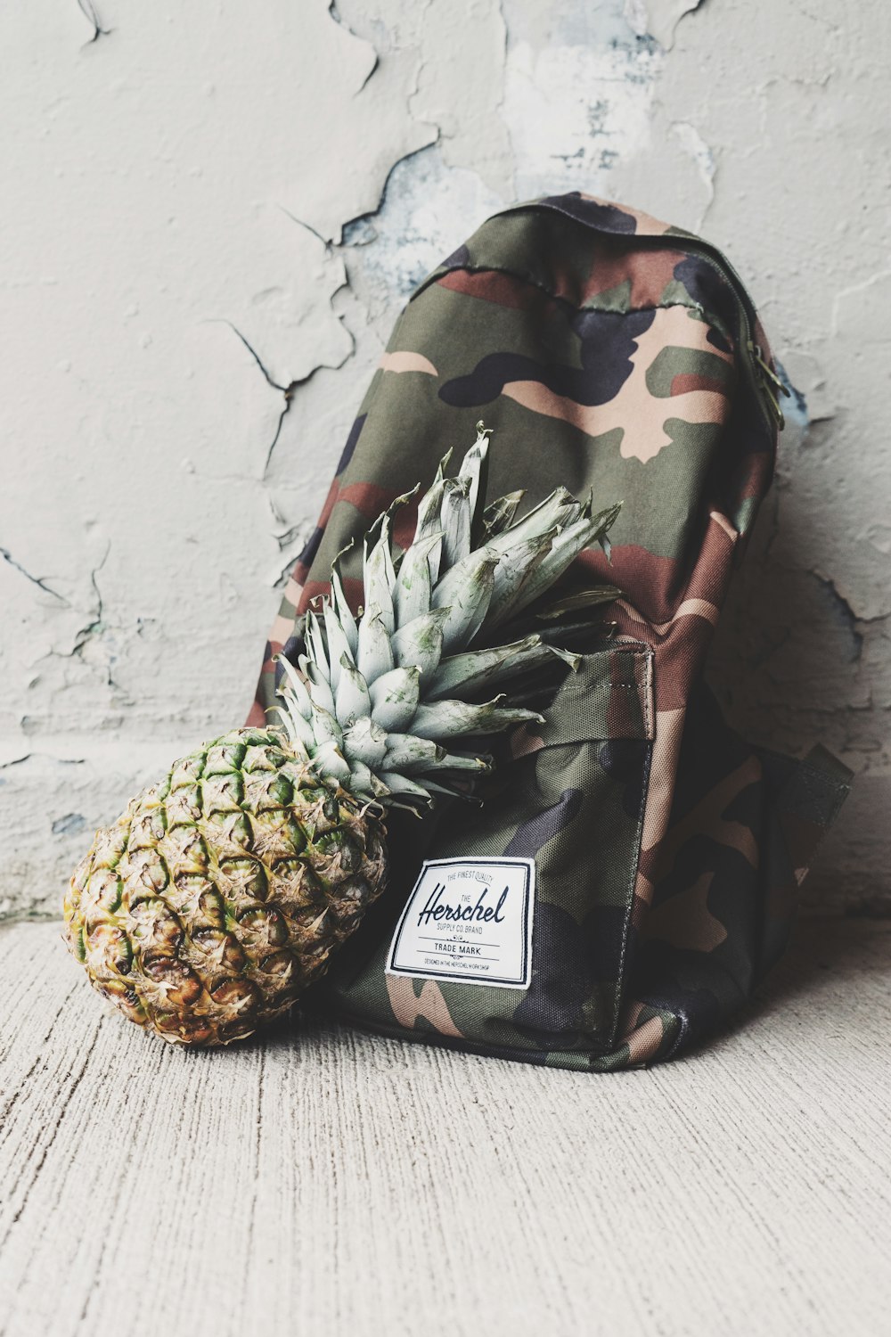 Fruta de abacaxi apoiada em mochila camuflada