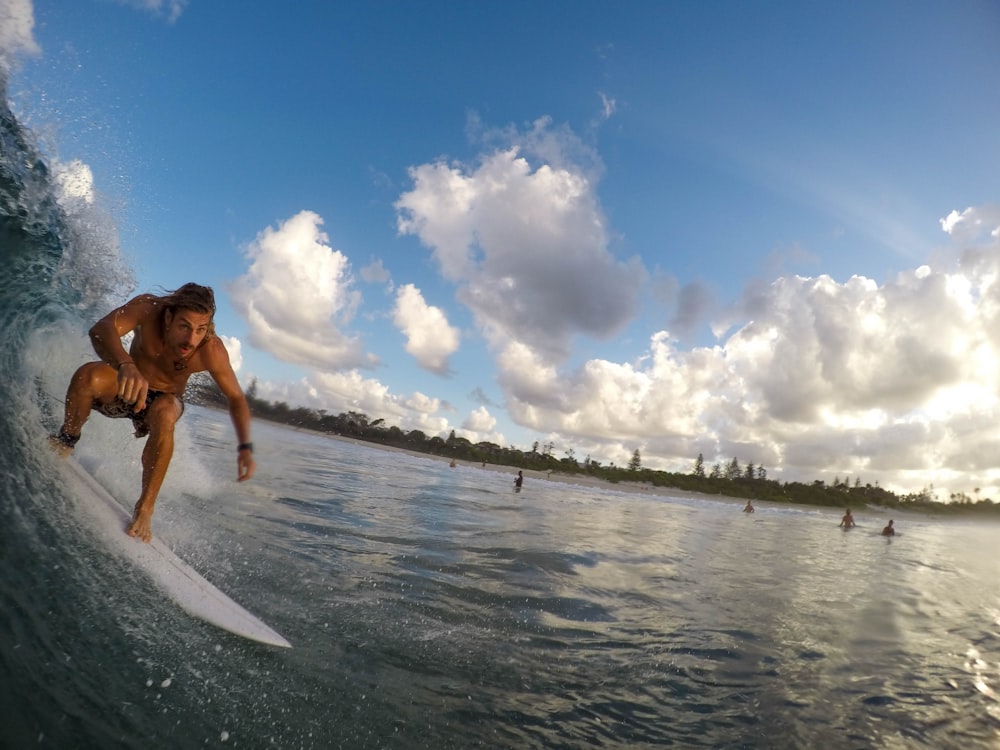 Une personne surfant sur une petite vague sur une plage animée.