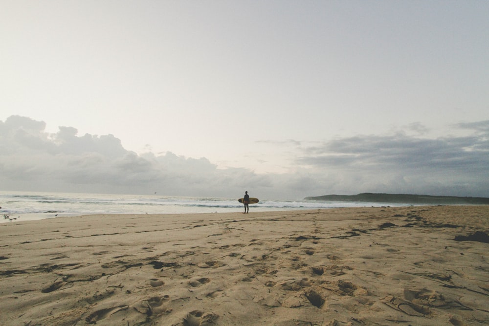 man standing by the seashore with surfboard