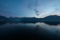 A peaceful lake surrounded by mountains at dawn.