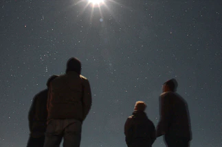 A welcoming group of diverse people looking up at a glowing starry sky.