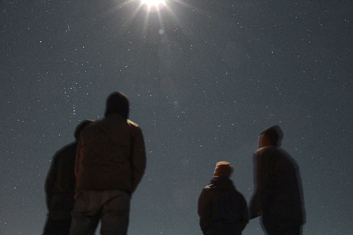 A welcoming group of diverse people looking up at a glowing starry sky.