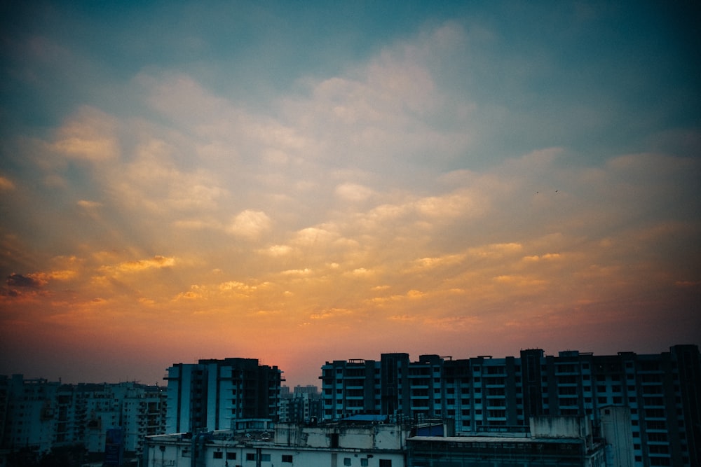 skyline della città sotto il cielo nuvoloso arancione e grigio durante il tramonto