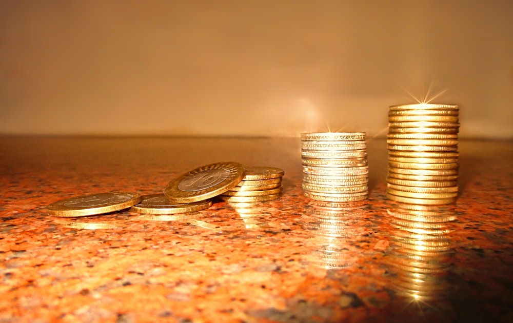 Stacked and loose coins on a countertop surface.