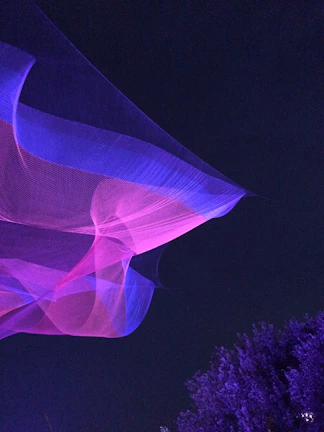 A whimsical veil fluttering in the breeze against a backdrop of twilight hues and twinkling lights.