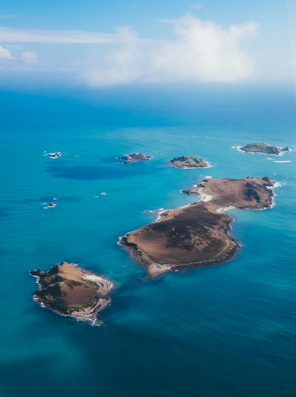 brown island on body of water under cloudy sky