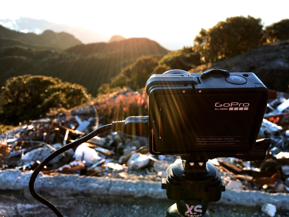 A GoPro camera set up on a tripod in a mountain area.