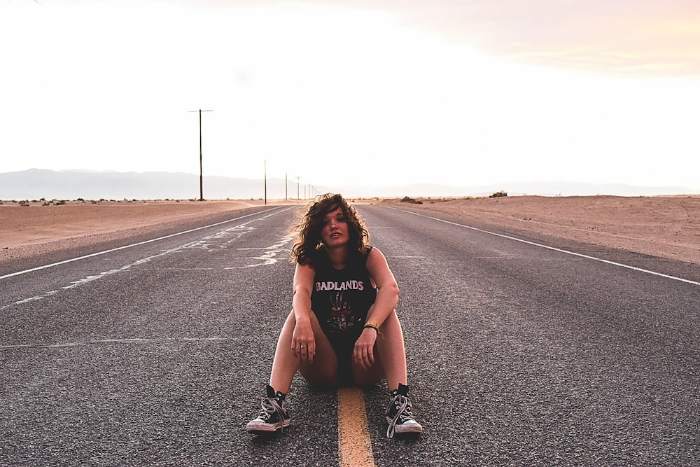 A rocker chick sitting on the yellow line in the middle of a road.