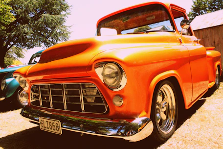 A shiny orange tow truck parked outside a modern automotive facility.