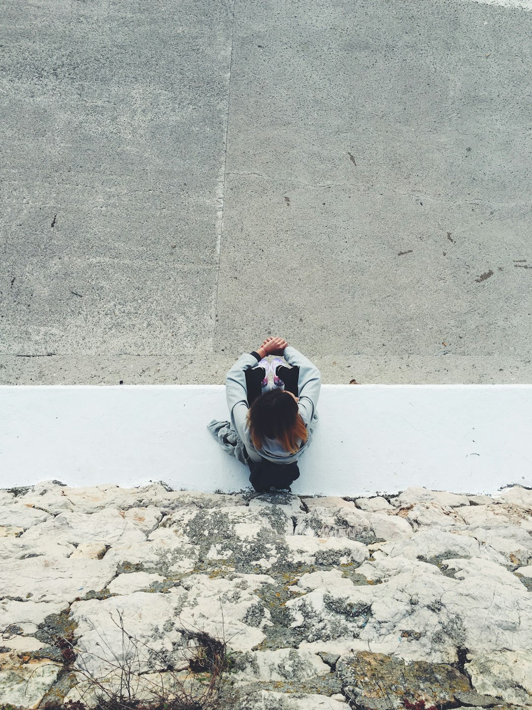 top view of person sitting near gray rock wall during daytime