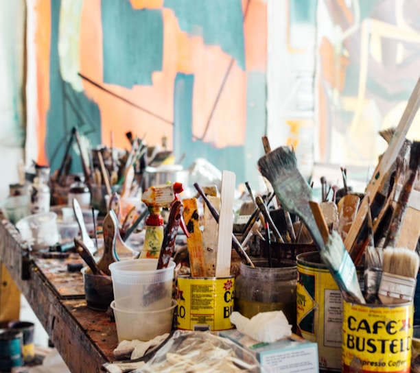 assorted-color paint brush on brown wooden table top