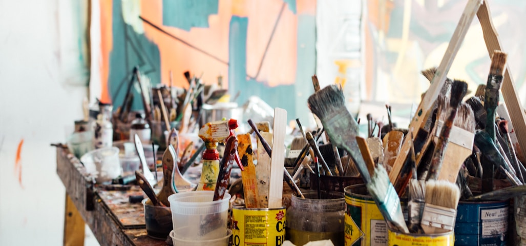 assorted-color paint brush on brown wooden table top