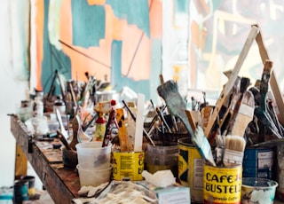 assorted-color paint brush on brown wooden table top