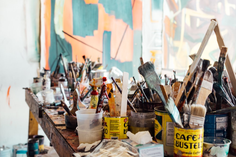 assorted-color paint brush on brown wooden table top