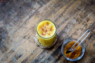 A refreshing glass of mango lassi topped with a sprinkle of cardamom powder.