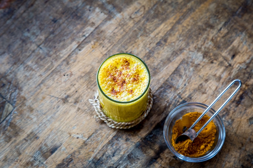 The top macro view of yellow cinnamon and an orange juice in a glass cup