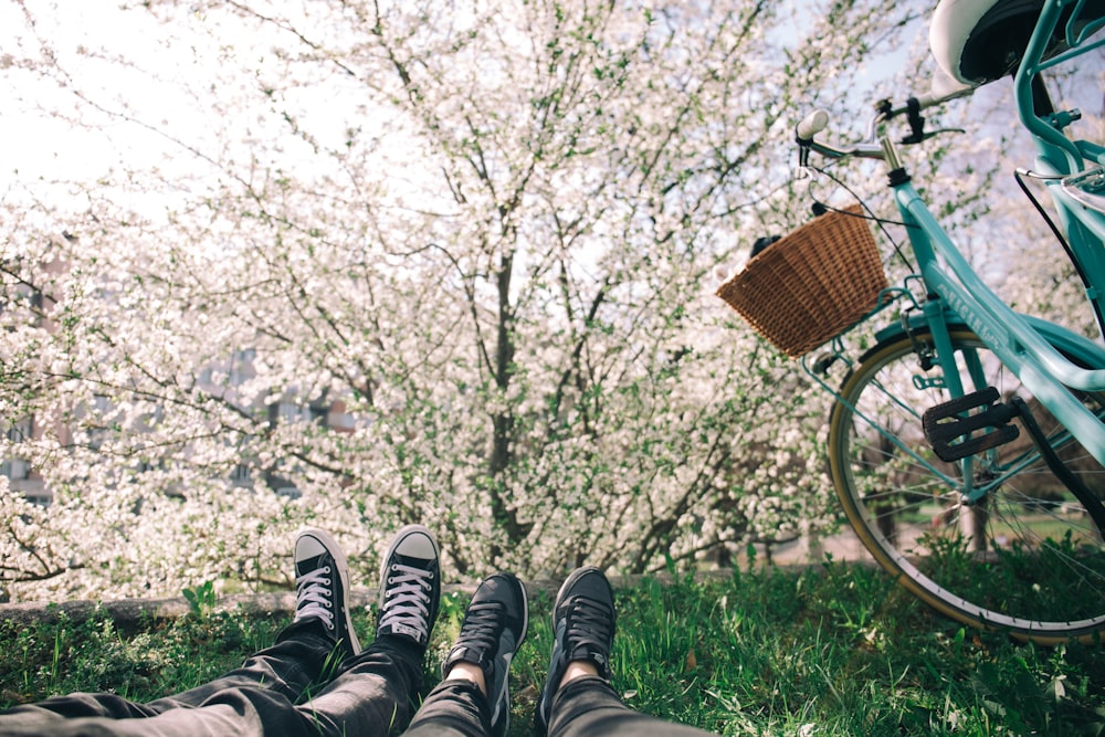 Zwei Personen liegen auf Gras in der Nähe von türkisfarbenem Citybike