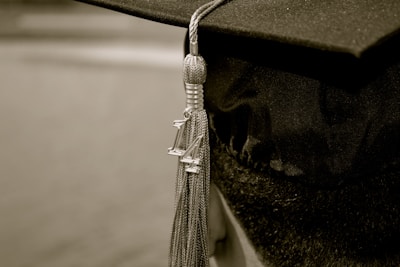 A graduation cap with a tassel adorned with the numbers '14', indicating the year of graduation. The cap is crafted from a black fabric material and the tassel is intricately detailed with metallic threads.